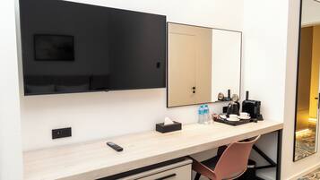 Habitación de hotel con escritorio, silla y un espejo grande.