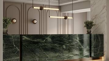 Un mostrador de recepción con encimera de mármol, luces colgantes y dos plantas en macetas.