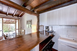 A kitchen with a wooden countertop, a coffee maker, and a sink.