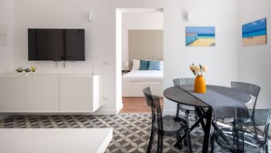 A modern hotel room with a flat-screen TV, a dining area with a table and chairs, and artwork on the walls. - Ci Capo 2 by Wonderful Italy (Palermo)