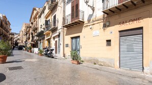 A narrow street lined with multi-story buildings, some with balconies and potted plants. - Ci Capo 2 by Wonderful Italy (Palermo)