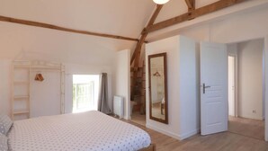Un dormitorio con cama, armario, espejo y puerta que da a otra habitación.