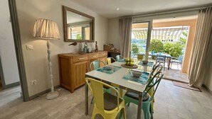 A dining area with a table set for four, chairs, a wooden cabinet, a floor lamp, and a view of the outdoors through a glass door. - 3-bedroom apartment with terrace in Saint-Cyprien (Saint-Cyprien)