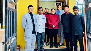 Un groupe de personnes se tient devant un bâtiment sur lequel est apposée une enseigne indiquant : « TRIPOO POTALA PALACE, un  établissement du groupe TRIPOO HOTELS & RESORTS ».