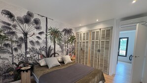A bedroom with a bed, a wall mural, wooden shutters, and a door leading to another room. - Villa with swimming pool, very quiet, near Cannes/Juans les pins (Vallauris)