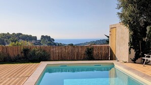 A rectangular swimming pool with clear blue water, surrounded by a wooden deck and a bamboo fence. - Villa with swimming pool, very quiet, near Cannes/Juans les pins (Vallauris)