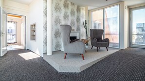 A modern living room with two grey armchairs, a white fireplace, and a large sliding glass door to the outdoors. - Vacation in the vacation apartment Morgenröte with sauna and terrace centrally located in Mirow (Mirow)