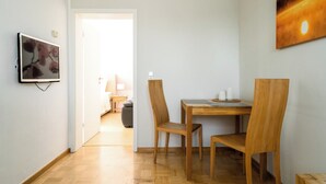 A dining area with a wooden table and chairs, a painting on the wall, and a door leading to another room. - Vacation in the vacation apartment Morgenröte with sauna and terrace centrally located in Mirow (Mirow)