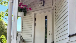 A white wooden front door with a small window above it, a number '22B' sign, and a set of wooden stairs leading up to the entrance. - Villa Mosahiisi Charming Poolside Getaway (Helsinki)