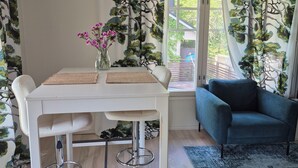 A dining area with a white table, bar stools, and a blue couch. - Villa Mosahiisi Charming Poolside Getaway (Helsinki)