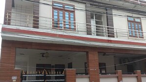 A two-story building with a garage entrance, a metal gate, and a parked car. - Ashiyana Upvan Homestay (Lucknow)