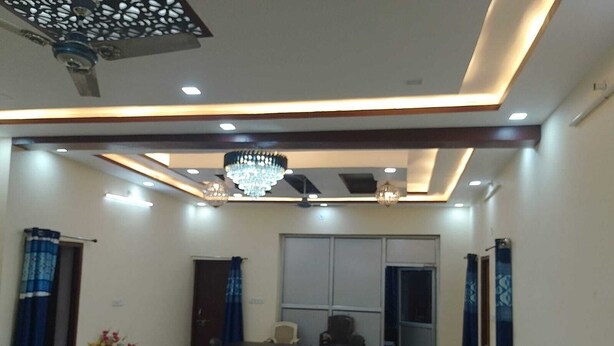A spacious room with a dining area, a chandelier, and a ceiling fan. - Ashiyana Upvan Homestay (Lucknow)