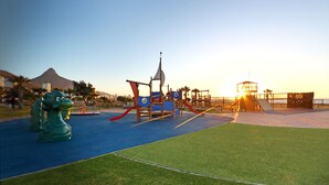 Un parque infantil con tobogán, estructuras para escalar y una pequeña torre.