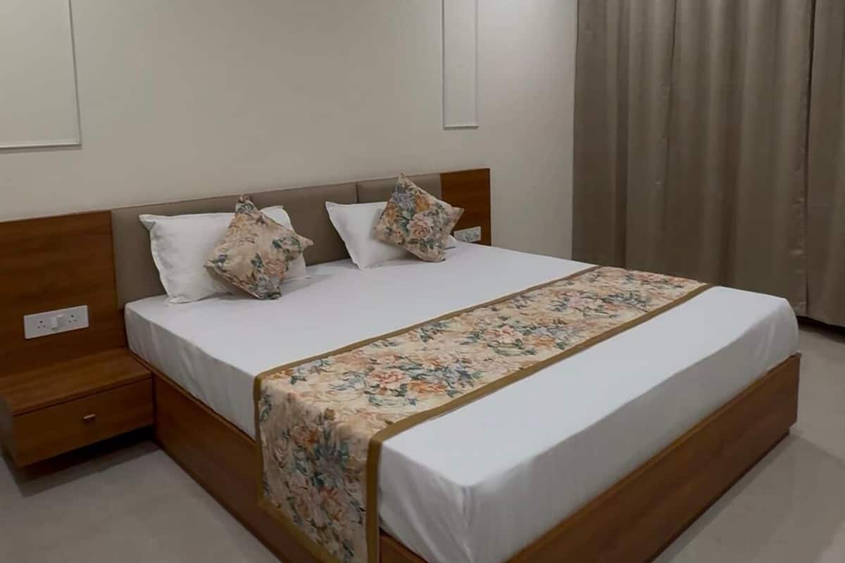 A modern bedroom with a wooden bed, white bedding, and a floral throw.