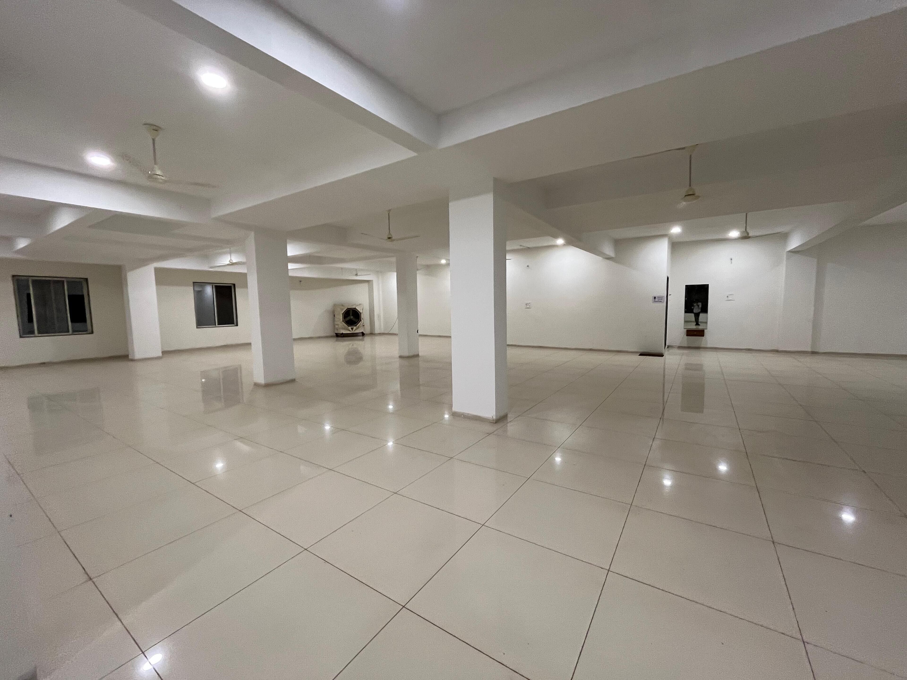 A spacious, well-lit interior with a high ceiling, tiled floors, and multiple windows.