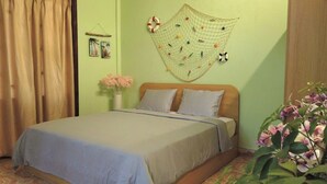 A bedroom with a bed, a wall hanging, and a plant.