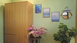 A room with a wooden wardrobe, a small table with a floral arrangement, and a potted plant.