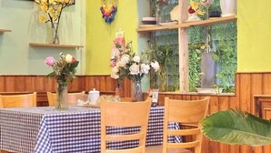 A dining area with checkered tablecloths, wooden chairs, and floral centerpieces.