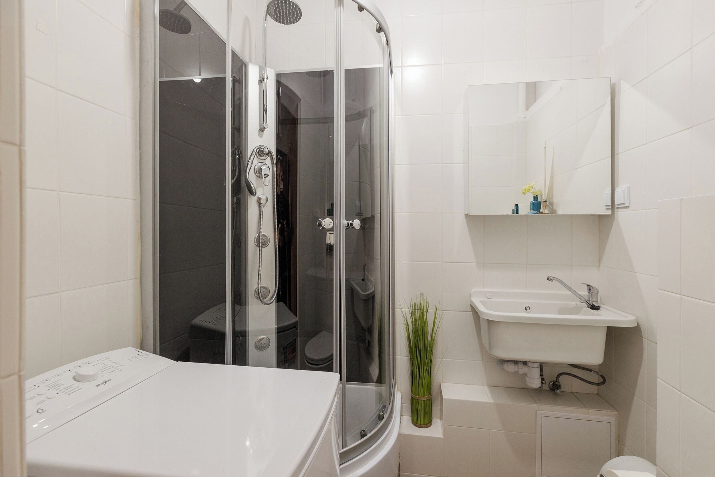 Ein modernes Badezimmer mit einer Duschkabine, einem weißen Waschbecken und einer Toilette.