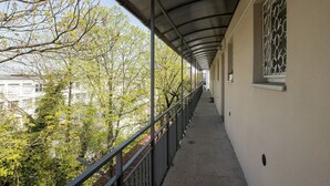 A covered corridor with a metal roof, a railing, and a view of trees and buildings. - ShortStayPoland Sielecka B183 (Warsaw)