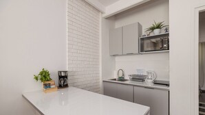 A compact kitchen with white cabinets, a white countertop, a microwave, and a sink. - ShortStayPoland Sielecka B183 (Warsaw)