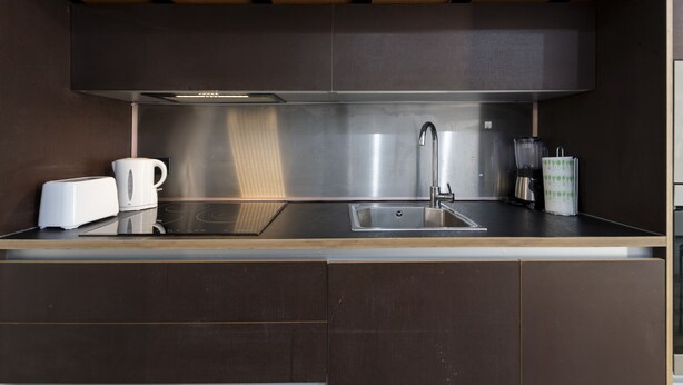 A modern kitchen with a stainless steel sink, a toaster, and a coffee maker.