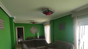 Un salon aux murs verts, avec un canapé, une table basse et un tapis à motifs.