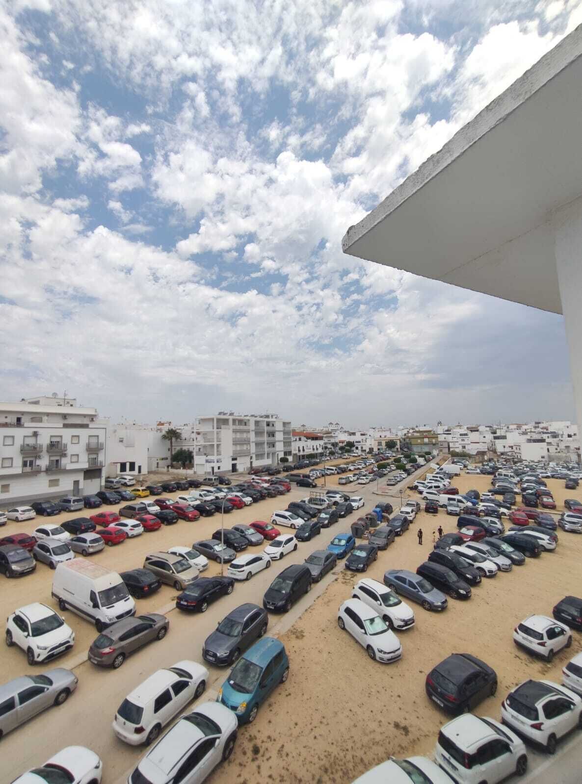 A parking lot with multiple cars and buildings in the background.