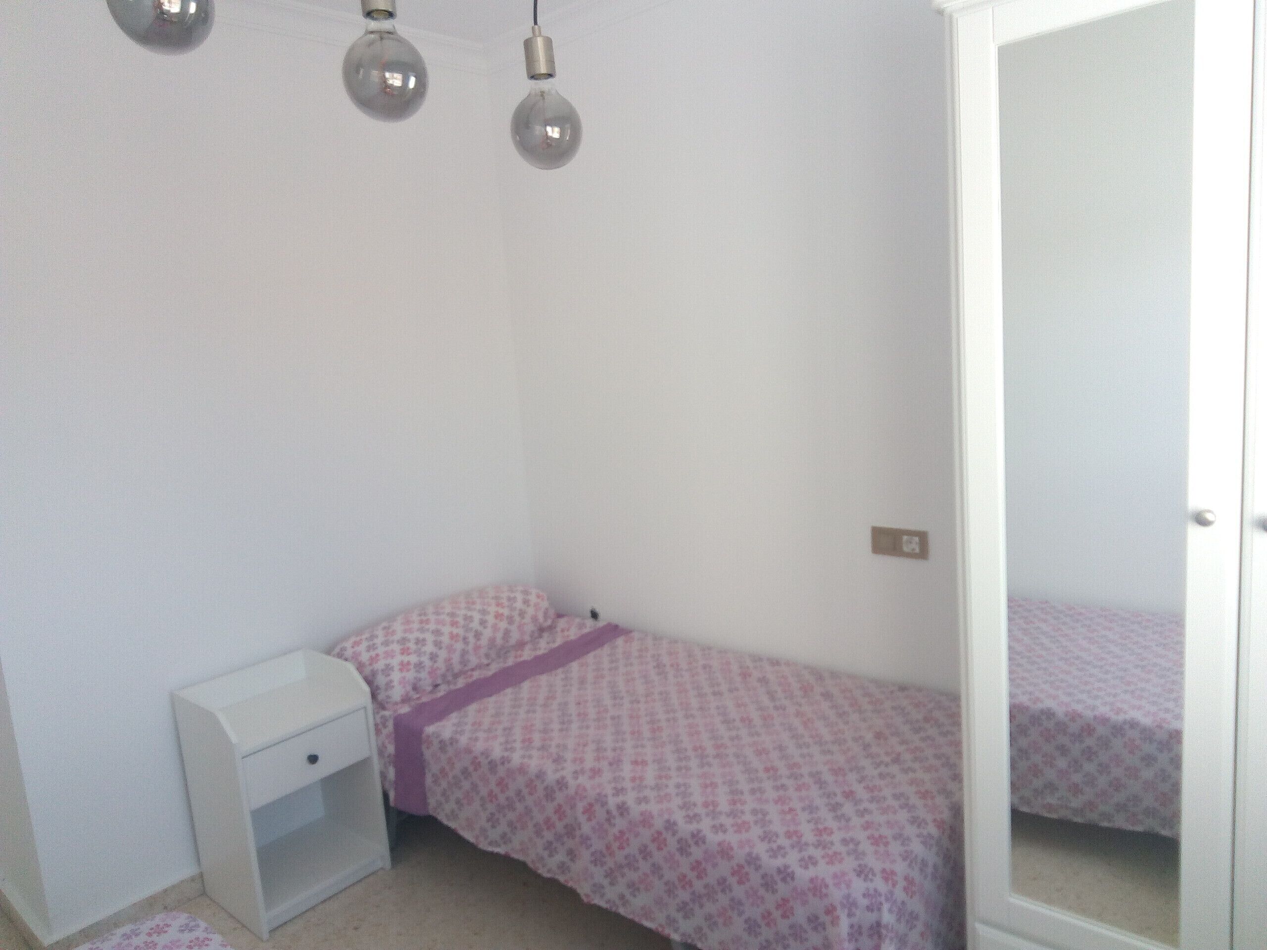 Ein kleines, ordentliches Schlafzimmer mit einem Einzelbett, einem Nachttisch und einem Kleiderschrank.
