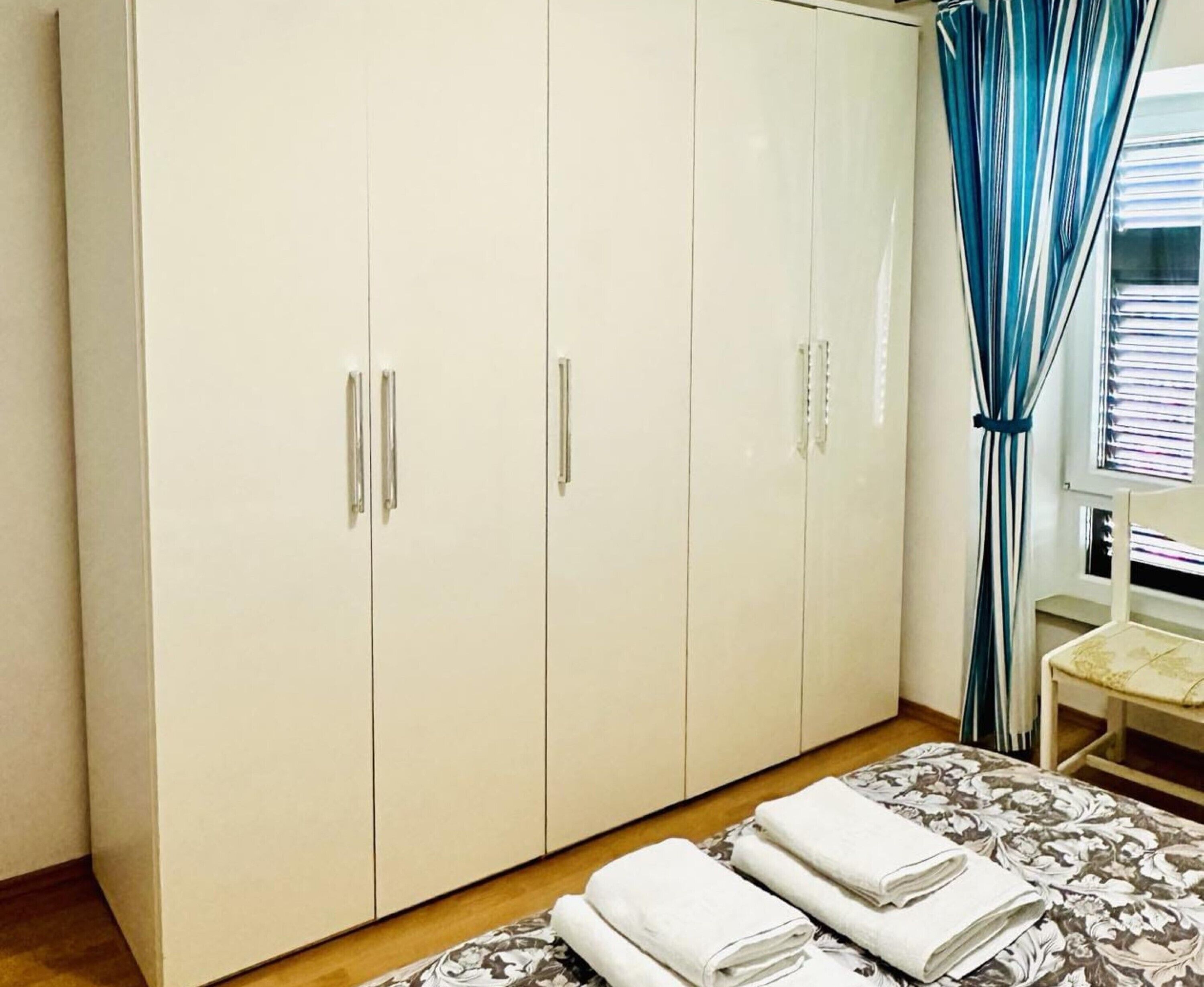 A bedroom with a bed, a wardrobe, and a chair.