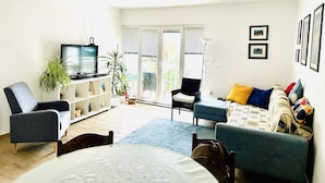 A living room with a TV, sofa, chairs, a bookshelf, and a window with blinds. - Luxury apartment Ivone with balcony (Rijeka)