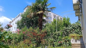 A multi-story building with balconies, surrounded by lush greenery and flowering plants. - Luxury apartment Ivone with balcony (Rijeka)