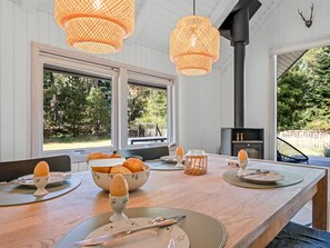 A dining area with a long wooden table set for four, large windows, and a black wood stove. - "Ottil" - 1.5km from the sea by Interhome (Blåvand)