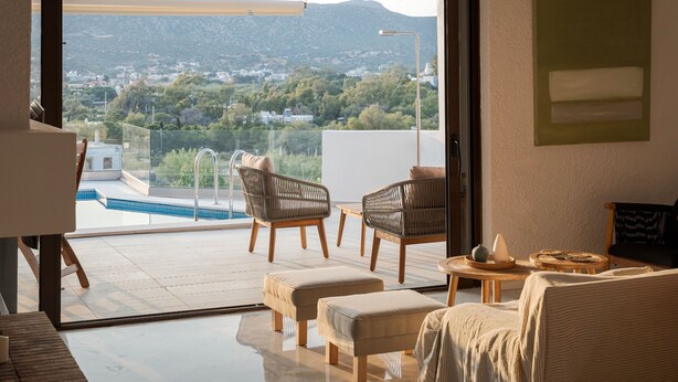 Un moderno salón con un amplio ventanal corredera que da a un balcón con vista a la piscina.