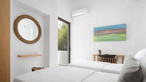 Una habitación de hotel moderna con dos camas, un ventanal grande, un aire acondicionado de pared, un espejo redondo, un estante y un cuadro.