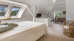 A bedroom with a bed, a desk, a chair, and a TV.