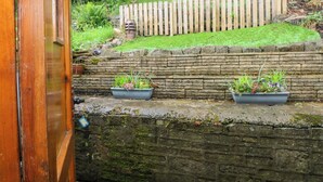 Un mur de pierres avec deux jardinières, une clôture en bois et une porte en bois.