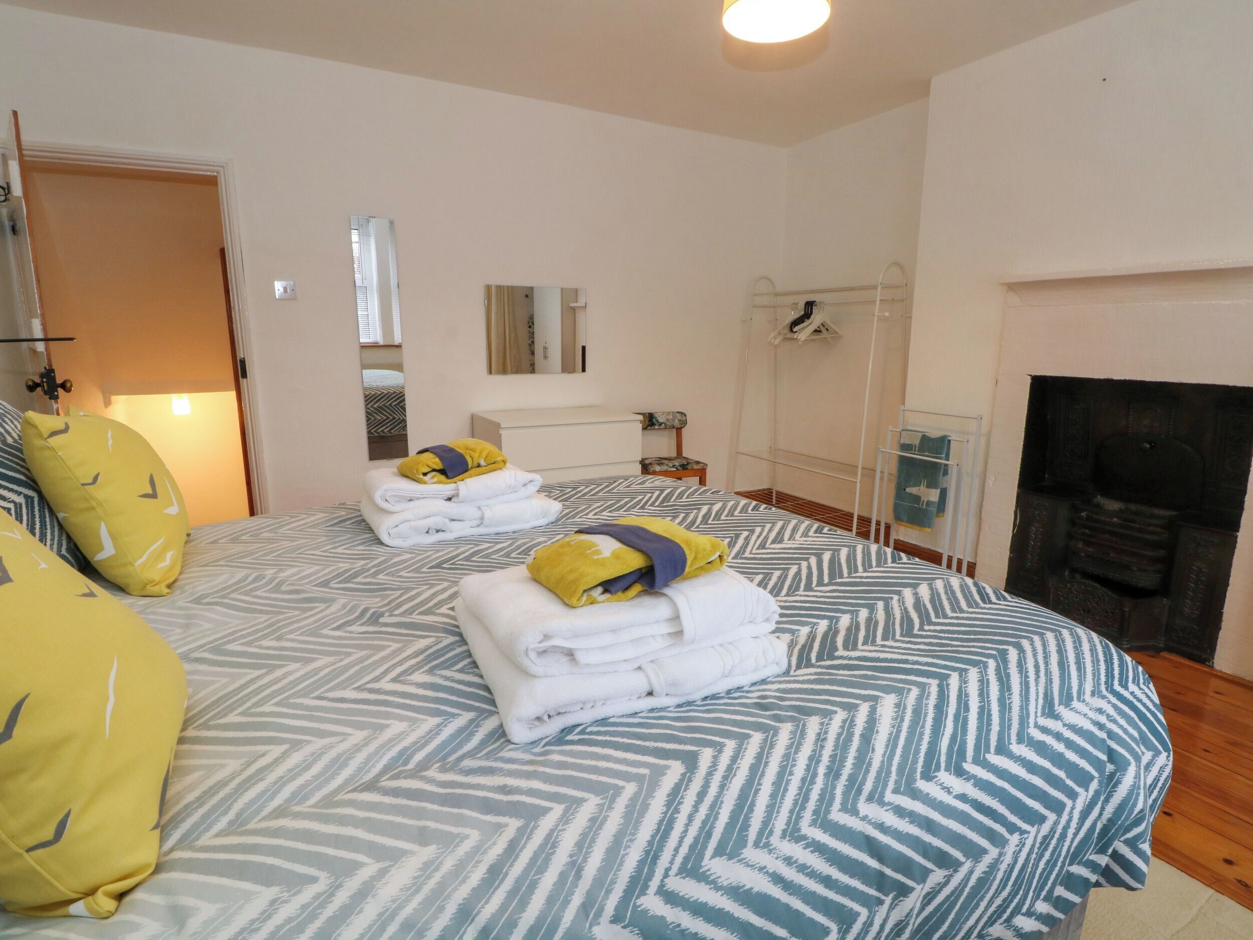 Een hotelkamer met een bed, een spiegel, een open haard en een deur.