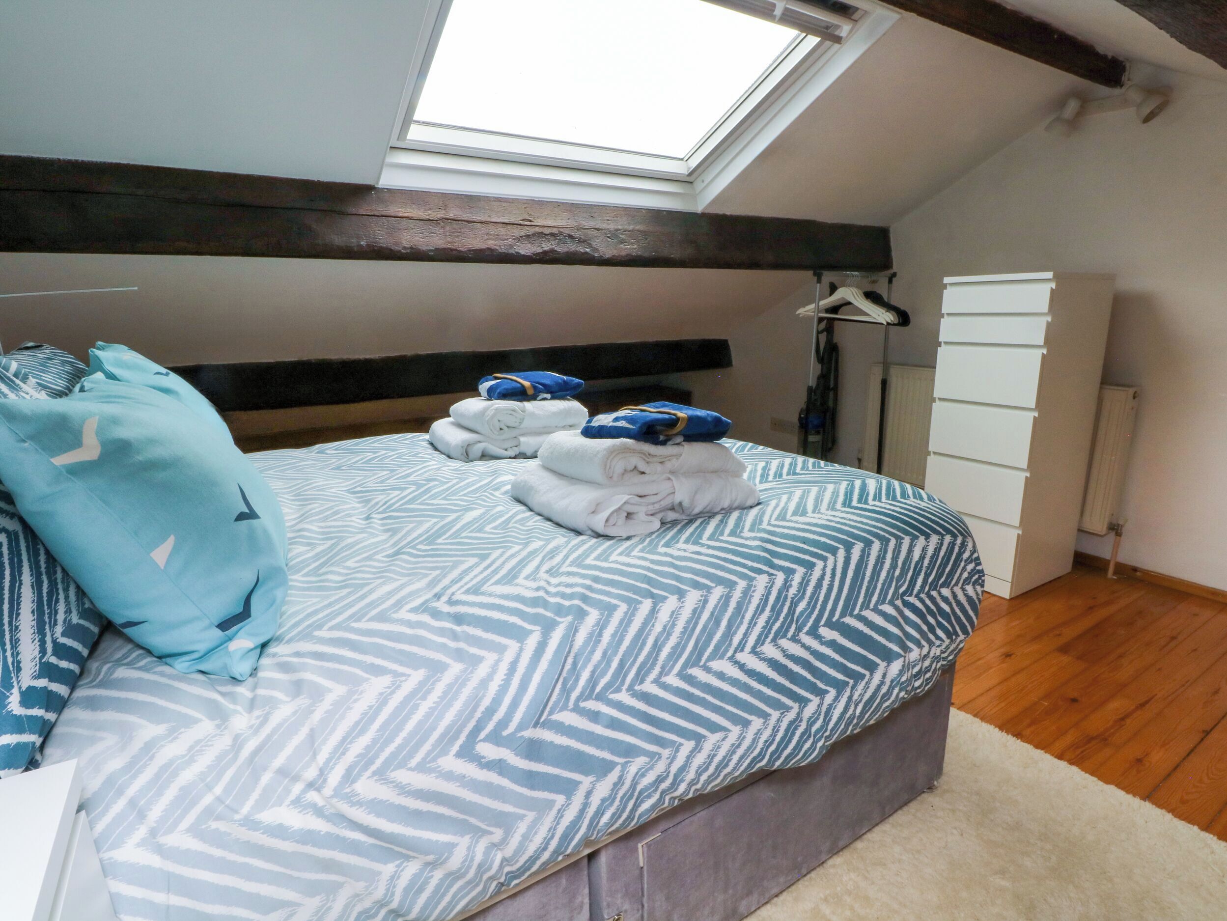 A bedroom with a bed, a skylight, a wardrobe, and a radiator.