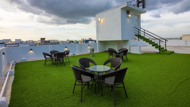 A rooftop terrace with artificial grass, outdoor seating, and a small white building with a staircase. - Housr 50 Luxury Rooms Near Cyber Tower (Hyderabad)