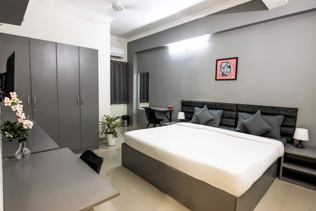 A modern bedroom with a large bed, a desk, and a wardrobe.