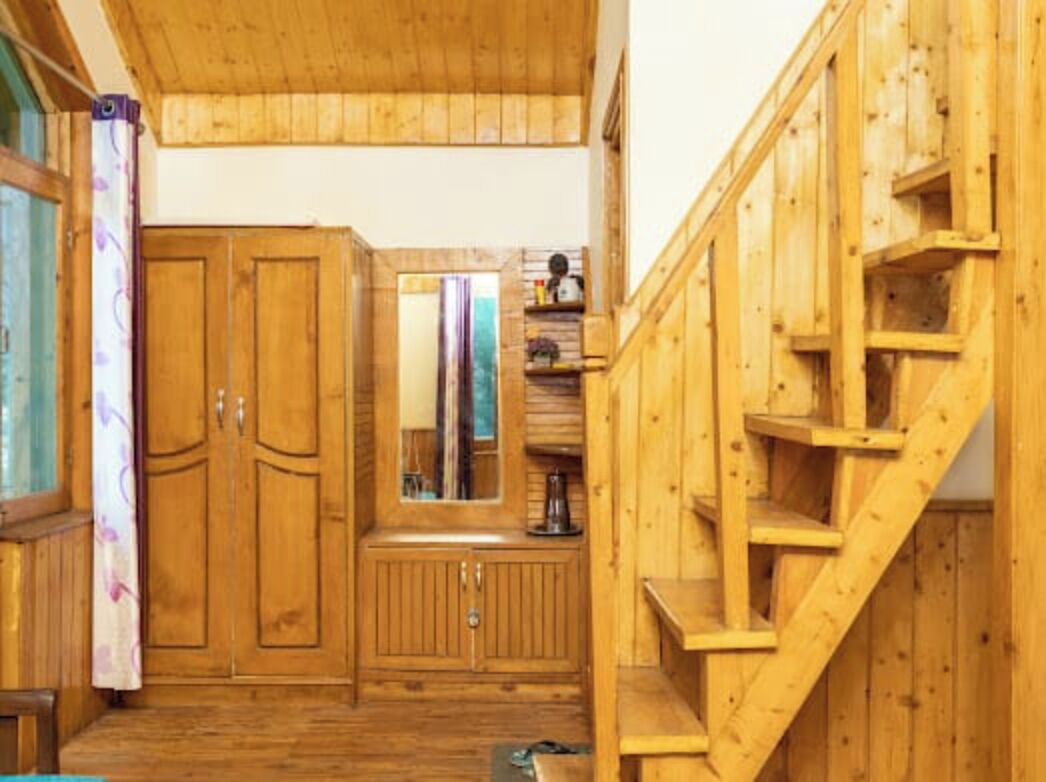 Un interior de madera con una escalera, armarios de madera y un espejo.
