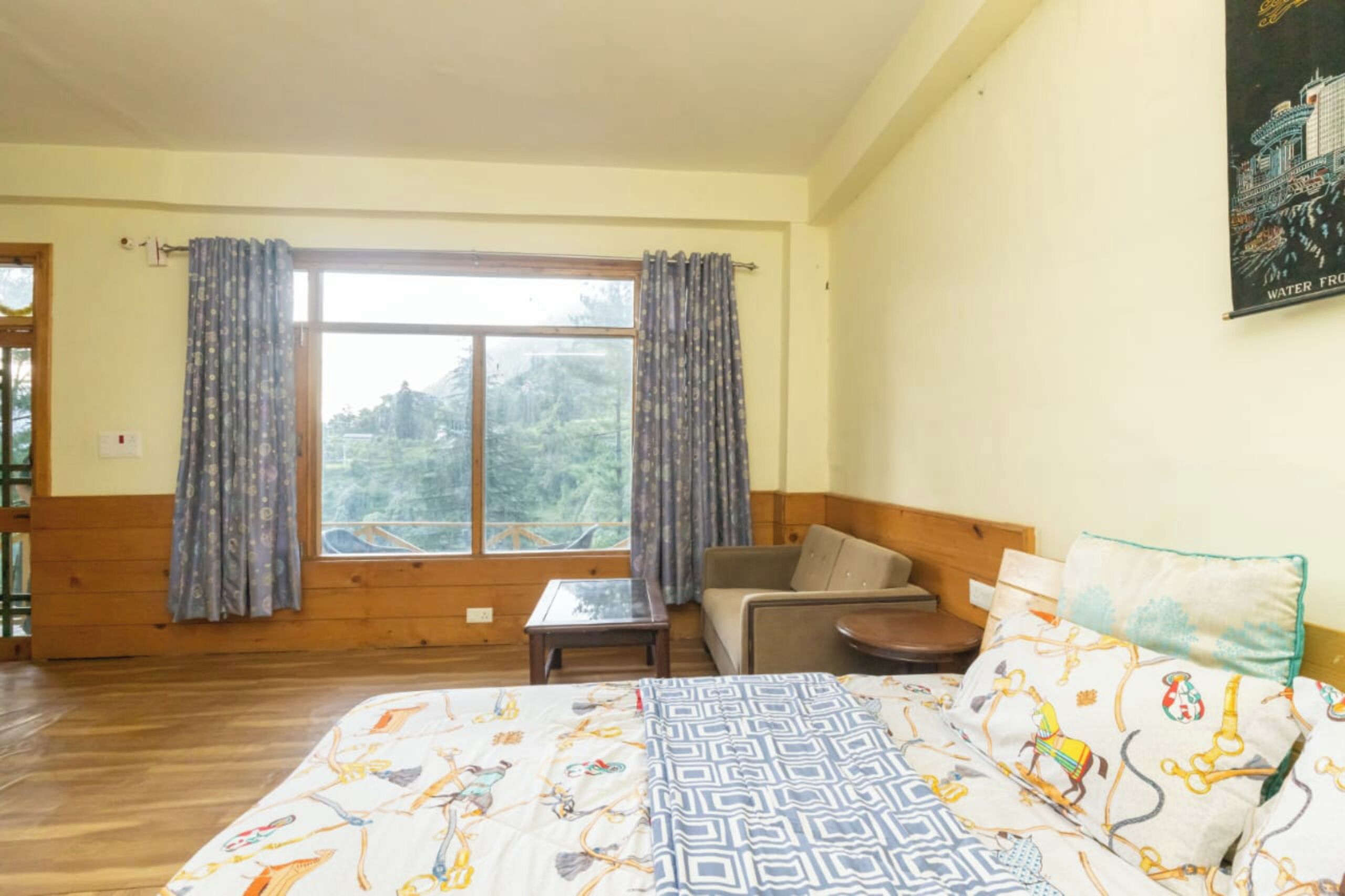 A room with a bed, a sofa, a small table, and a window with curtains.