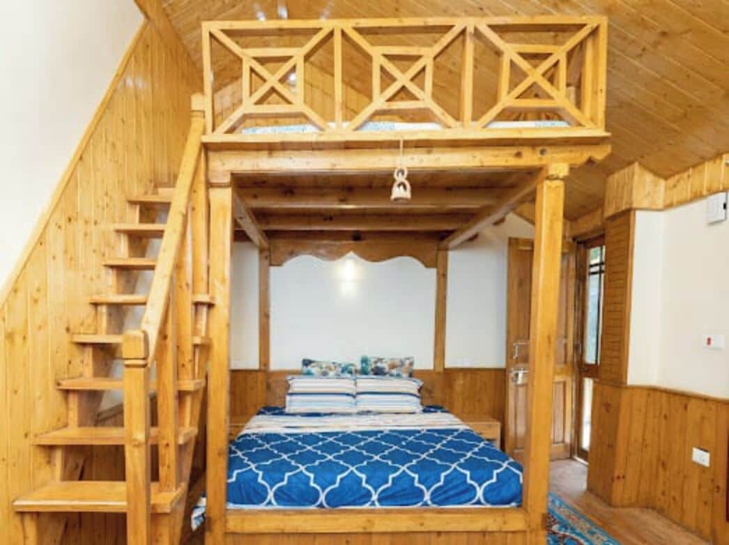 Ein Holzraum mit einem Etagenbett, einer Stehleiter und einer Holzbalkenkonstruktion an der Decke.