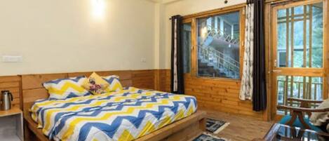 A wooden-framed room with a bed, a small table, and a window with curtains.
