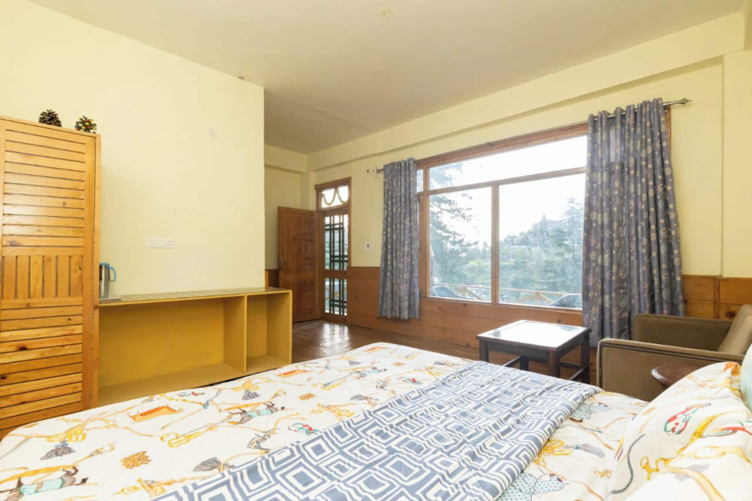 Une chambre à coucher avec un lit, une petite table, une chaise, une armoire et une fenêtre avec des rideaux.