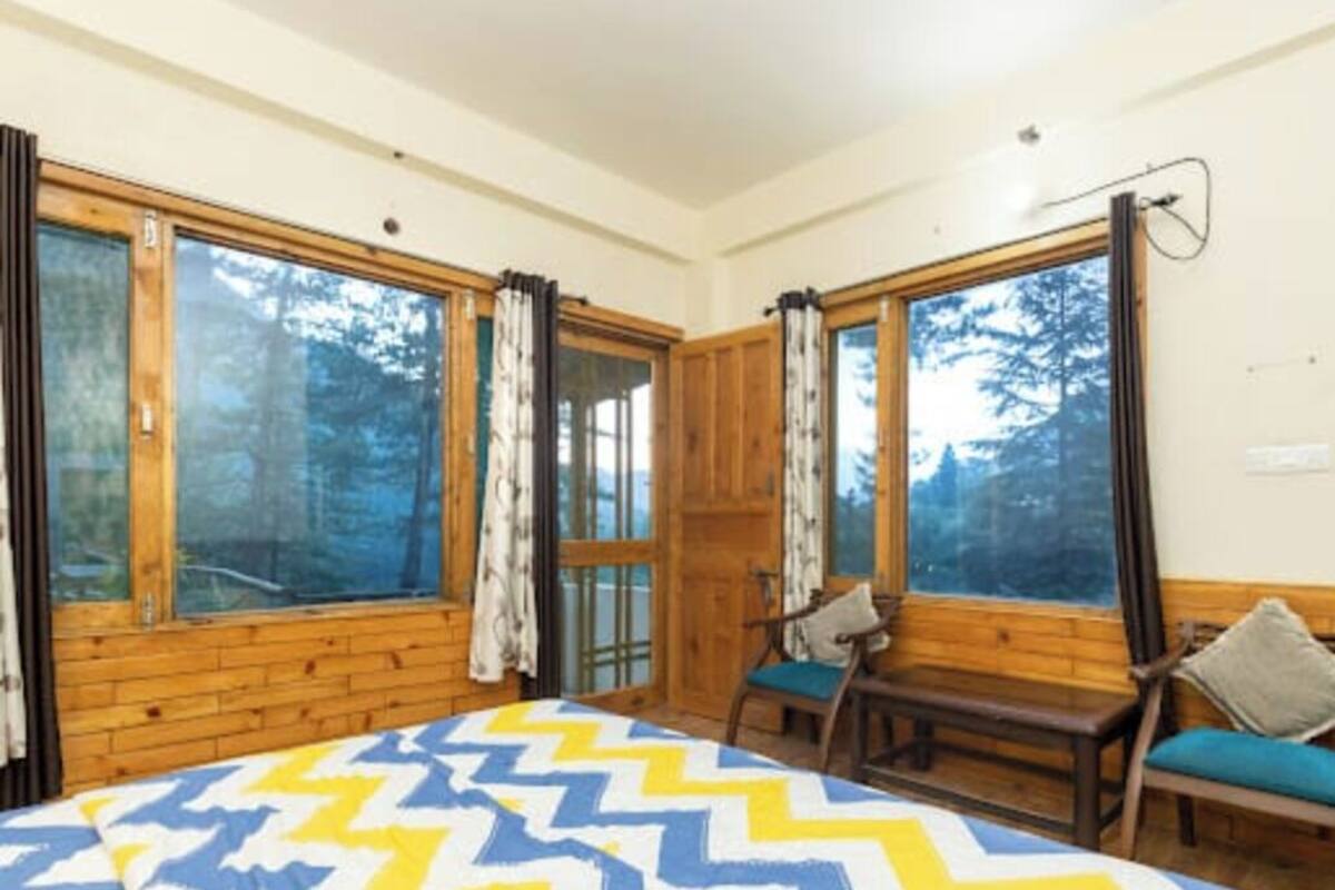 A room with a bed, two windows, wooden walls, and a bench.