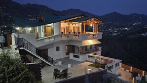 A multi-story house with a balcony, a staircase, and a patio area. - Laspa Cottage (Bhimtal)