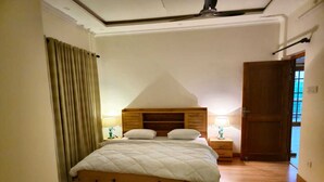A bedroom with a wooden bed, two bedside tables with lamps, a wooden wardrobe, and a window with curtains. - Laspa Cottage (Bhimtal)
