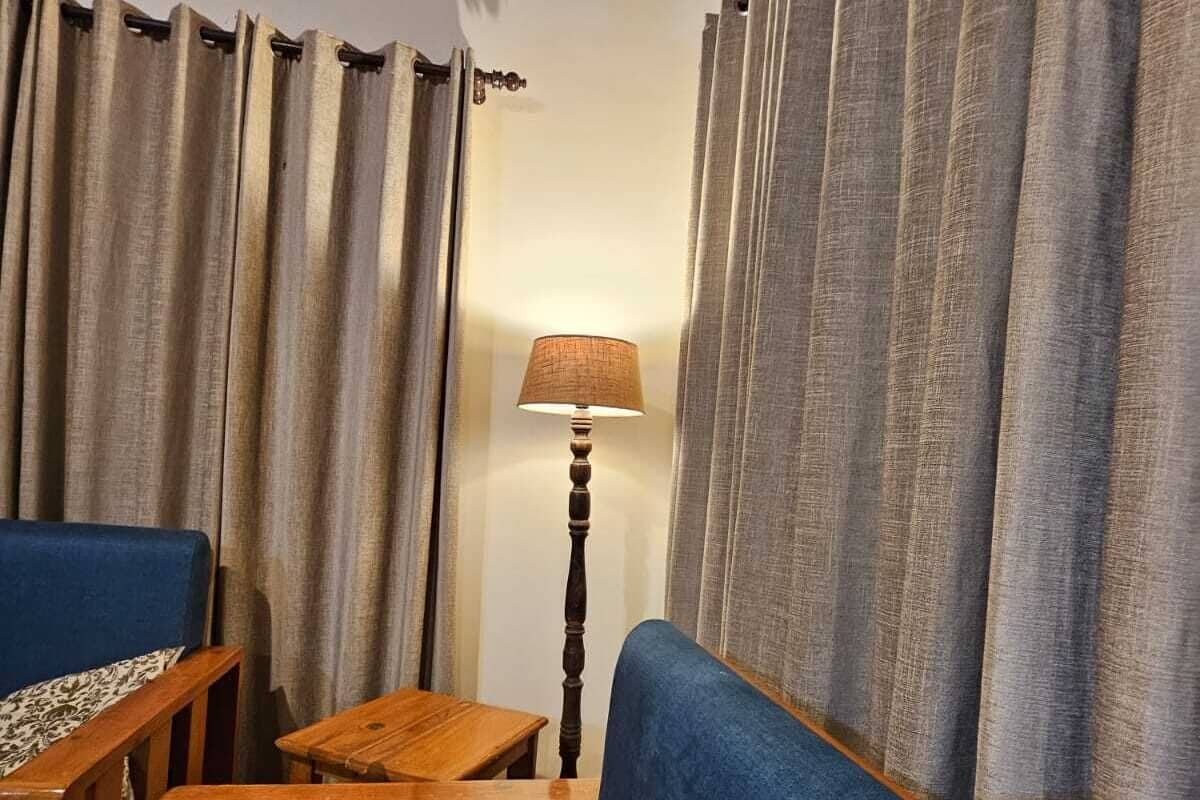 A cozy living room with a blue sofa, wooden side tables, and a lamp.